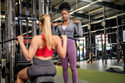 Fitnesstrainerin leitet Kundin an