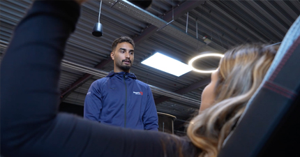 Trainer leitet Kundin an. Sie drückt Gewichte.