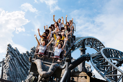 Leute mit nach oben gestreckten Armen in einer abwärts sausenden Achterbahn im Phantasialand.